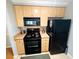 Efficient kitchen layout with black appliances and light wood cabinets at 105 S Obrien St # 213, Tampa, FL 33609