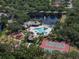Aerial view of community pool, tennis courts, and playground surrounded by lush greenery and a serene lake with a fountain at 11713 Goldenrod Ave, Bradenton, FL 34212