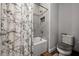 Stylish bathroom featuring tiled shower with glass doors, a white marble-patterned shower curtain, and ample space at 11713 Goldenrod Ave, Bradenton, FL 34212