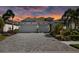 Charming home featuring a three-car garage, a paved driveway, and lush landscaping illuminated by a striking sunset sky at 11713 Goldenrod Ave, Bradenton, FL 34212