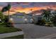 A charming home with a paved driveway leading to a three-car garage, enhanced by lush landscaping and a sunset backdrop at 11713 Goldenrod Ave, Bradenton, FL 34212
