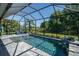 Screened-in pool area featuring a pristine pool, stone accents, and meticulously landscaped surroundings at 11713 Goldenrod Ave, Bradenton, FL 34212