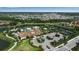 Aerial view of community center with pool, tennis courts, and parking, set amongst lush greenery at 12012 Legacy Estates Blvd, Sarasota, FL 34238