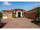 Exterior features beautiful desert landscaping, a brick driveway, and neutral stucco at 12012 Legacy Estates Blvd, Sarasota, FL 34238