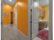 Hallway with hardwood floors and vibrant orange walls leading to the laundry area with cabinets at 12012 Legacy Estates Blvd, Sarasota, FL 34238