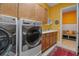 Laundry room with front load washer and dryer and cabinets, leading to the hallway with seating at 12012 Legacy Estates Blvd, Sarasota, FL 34238