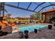 Sparkling screened-in pool featuring a brick deck, lush plants, and serene water views at 12012 Legacy Estates Blvd, Sarasota, FL 34238