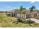 A cream-colored home with a three-car garage, arched entry, a red tile roof, and lush front yard landscaping at 12640 Felice Dr, Venice, FL 34293