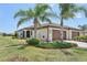 A cream-colored home with a three-car garage, manicured landscaping, and towering palm trees in a sunny setting at 12640 Felice Dr, Venice, FL 34293