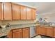 Kitchen featuring granite counters, wood cabinets, and stainless steel dishwasher and oven at 12640 Felice Dr, Venice, FL 34293