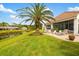 Serene backyard with lush green lawn, palm trees, a lake view, and comfortable patio seating at 128 Braemar Ave, Venice, FL 34293
