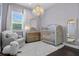 Charming Bedroom with elegant crib, plush chair, and decorative chandelier lighting at 13319 Deep Blue Pl, Bradenton, FL 34211