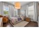 Neutral bedroom with hardwood floors, pendant light fixture, large windows with white curtains, and artwork at 13319 Deep Blue Pl, Bradenton, FL 34211