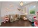 Charming Bedroom with pink floral wall, chandelier, crib, dresser, rocking chair, and hardwood floors at 13319 Deep Blue Pl, Bradenton, FL 34211