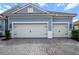 Attached two-car garage with white doors, black hardware, and paved driveway on this attractive blue home at 13319 Deep Blue Pl, Bradenton, FL 34211