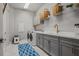 Contemporary laundry room equipped with stainless steel washer/dryer and gray storage cabinets at 13319 Deep Blue Pl, Bradenton, FL 34211