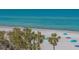 Beach view showcasing white sands and turquoise waters, framed by lush palm trees and beach umbrellas at 1701 Gulf Of Mexico Dr # 502, Longboat Key, FL 34228