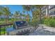 Outdoor grill area with tropical plants and palm trees in the background at 1701 Gulf Of Mexico Dr # 502, Longboat Key, FL 34228