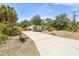 Home with a long driveway, a lush green yard with palm trees, and inviting curb appeal at 1709 Kerman St, North Port, FL 34288