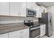Close-up of the kitchen area with stainless steel oven, microwave, granite counters and white cabinets at 1723 Fred Ives St, Ruskin, FL 33570