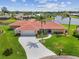 A sunny aerial view shows a charming home with a red tile roof, well-manicured lawn, and waterfront access at 1836 Ironwood Ct, Venice, FL 34293