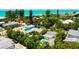 Aerial view of a beach home with a private pool surrounded by lush tropical trees with the ocean in the background at 205 Elm Ave, Anna Maria, FL 34216