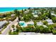 Aerial view of a colorful beach town neighborhood with homes surrounded by lush tropical landscaping near a white sand beach at 205 Elm Ave, Anna Maria, FL 34216
