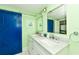 This bathroom features a double vanity, bright blue barn door and coastal decorations, adding a pop of color at 205 Elm Ave, Anna Maria, FL 34216