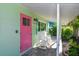 Inviting front porch with rocking chairs, a pink door, and manicured landscaping at 205 Elm Ave, Anna Maria, FL 34216