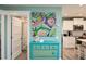 Hallway view of the kitchen and bathroom; vintage dresser with a colorful art piece above it at 205 Elm Ave, Anna Maria, FL 34216