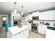 Bright kitchen features white cabinets, stainless steel appliances, and center island with modern pendant lighting at 205 Elm Ave, Anna Maria, FL 34216