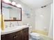 A bathroom with a wood vanity, white walls, and a shower-tub combo at 21300 Brinson Ave # 214, Port Charlotte, FL 33952