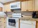 Close-up of kitchen featuring white appliances, granite counters, and wood cabinets at 21300 Brinson Ave # 214, Port Charlotte, FL 33952