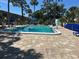 Community pool with chairs, umbrellas, and light-colored brick pool deck, perfect for relaxation on a sunny day at 21300 Brinson Ave # 214, Port Charlotte, FL 33952
