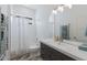 Bright bathroom with white tile, textured wall, modern vanity, large mirror, and decorative shower curtain at 2365 Novus St, Sarasota, FL 34237