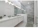 Bright bathroom featuring double sink, modern fixtures, walk-in shower with beautiful tile, and wood look floors at 2365 Novus St, Sarasota, FL 34237