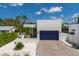 Modern home with a blue garage door, light-colored facade, front courtyard, and a brick driveway at 2365 Novus St, Sarasota, FL 34237