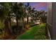 Picturesque backyard with lush landscaping, palm trees, and tranquil water views for serene outdoor living at 3302 Sabal Cove Ln, Longboat Key, FL 34228