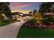 A home with a paved driveway, well-maintained landscaping, colorful flowers, and exterior lighting at 3302 Sabal Cove Ln, Longboat Key, FL 34228