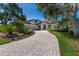 Lovely home with a brick driveway, mature trees, and flowering plants at 3302 Sabal Cove Ln, Longboat Key, FL 34228