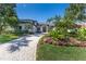 Beautifully landscaped front yard with a winding paver driveway and lush tropical plants at 3302 Sabal Cove Ln, Longboat Key, FL 34228