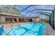 View of the enclosed pool area with patio, lounge chairs, and sliding glass doors to the home at 3608 Avenida Madera, Bradenton, FL 34210
