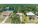 Aerial view of a home featuring an in-ground pool and lake access amid lush greenery at 410 136Th E Ct, Bradenton, FL 34212