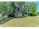 A view of a grassy backyard with mature trees and a partial view of the lake behind the property at 410 136Th E Ct, Bradenton, FL 34212