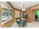 Dining area boasts pool views, glass table, and a charming chandelier for Gathering meals and gatherings at 410 136Th E Ct, Bradenton, FL 34212