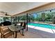 Covered patio area featuring a glass table, seating, fan, and a view of the inviting in-ground pool at 410 136Th E Ct, Bradenton, FL 34212
