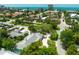 An aerial view shows proximity to the ocean and the street view of the house surrounded by trees and landscaping at 410 Garfield Dr, Sarasota, FL 34236