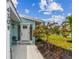 Inviting entrance with tile walkway, red flowering tree, and a charming covered front porch and blue exterior siding at 4309 Pinfish Ln, Palmetto, FL 34221