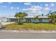 Charming one-story home with a blue exterior, well-manicured lawn, and lovely tropical landscaping and palm trees at 4309 Pinfish Ln, Palmetto, FL 34221