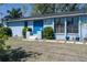 A cozy light blue home with a vivid blue front door framed by manicured bushes and light sconces at 4403 5Th W Ave, Palmetto, FL 34221